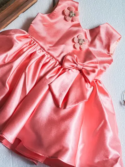 Another look at this charming salmon pink satin dress. The rich fabric and thoughtful details like the floral appliqués and bow sash make it a standout piece for any special occasion.