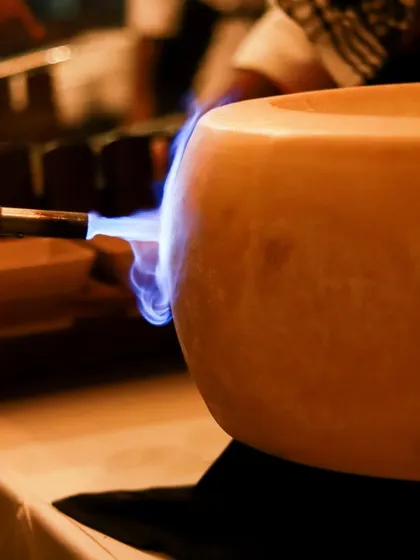 A chef uses a blowtorch on a wheel of cheese, melting it for a spectacular pasta dish.