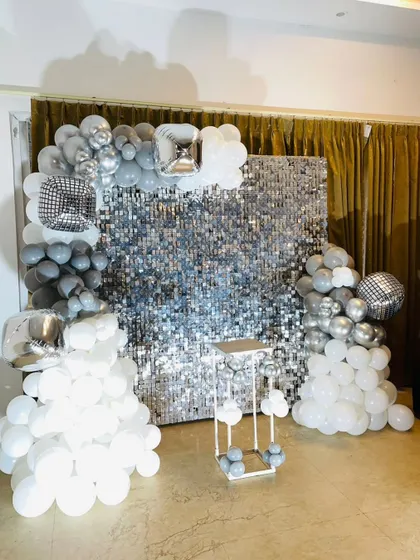 A silver shimmer wall framed by white and grey balloon clouds, a versatile backdrop for any celebration.