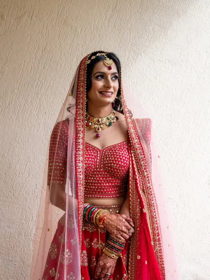 A beautiful portrait of the bride in her red lehenga, smiling happily on her wedding day.