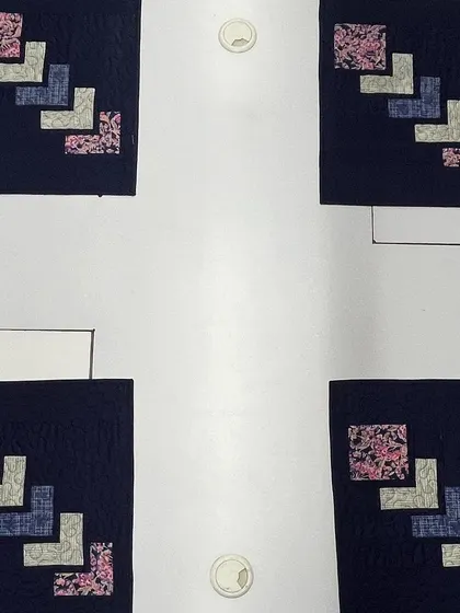 A set of four matching placemats with a modern geometric design. The navy blue background makes the floral and patterned fabrics pop.