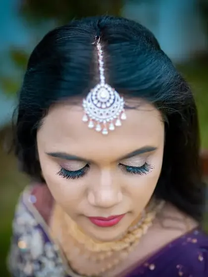 A close-up, top-down view of a bride, highlighting her beautiful maang tikka and flawless eye makeup.