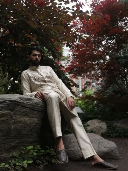 Set against a natural backdrop, the ivory mirror work kurta exudes a quiet confidence. It's a versatile piece, perfect for a daytime wedding event or an evening festival celebration.