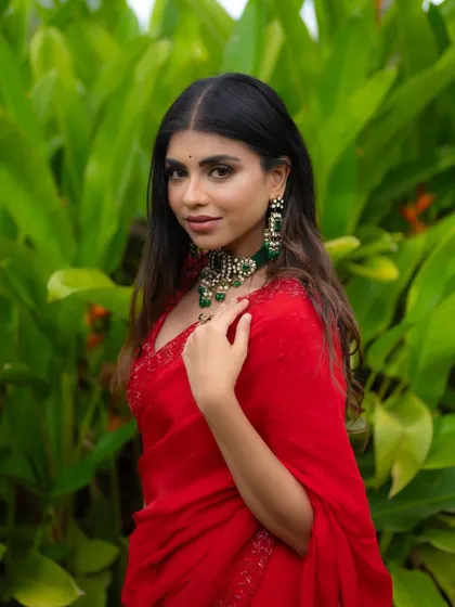 A classic portrait pose looking directly at the camera. Her confidence and the beauty of the red saree make for a powerful and striking image.