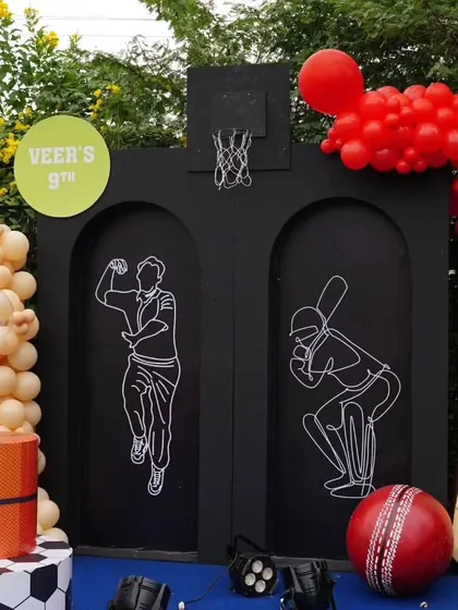 The decor features line-art cutouts of a bowler and batsman, along with giant cricket and basketball props.