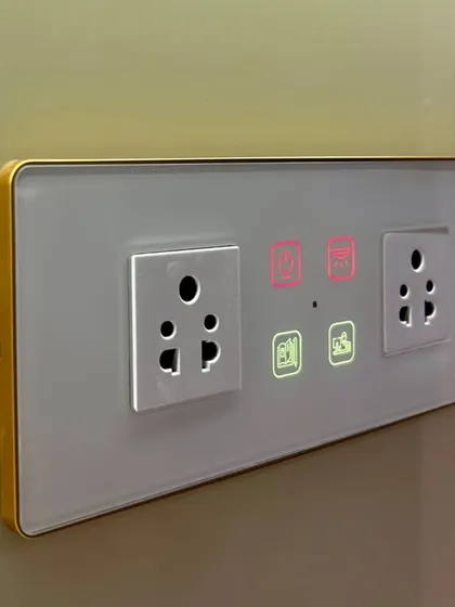 This custom panel features a white glass finish with a gold frame, designed to match the client's luxurious interior. It includes two sockets for added utility.