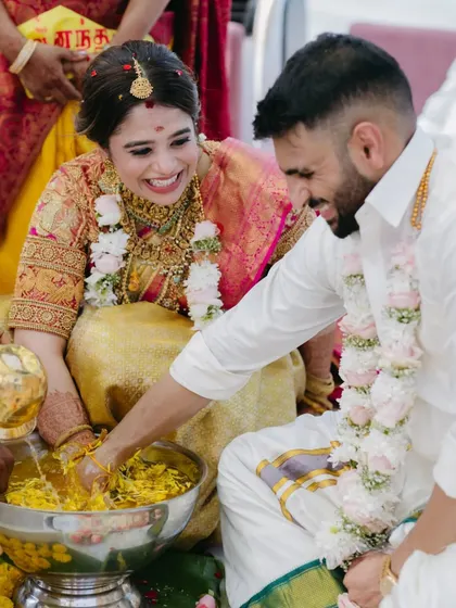 A joyful moment from a South Indian wedding ritual, where the couple laughs while participating in a traditional game.