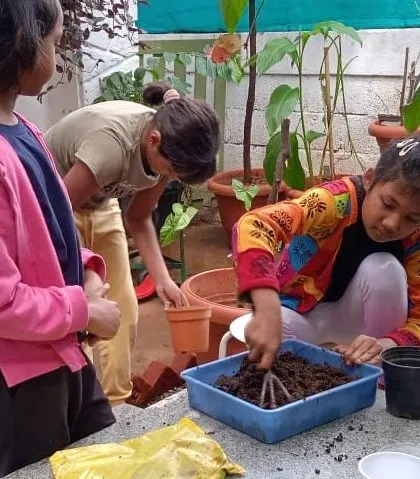 Children get their hands dirty preparing soil for a gardening experiment, learning about soil composition and what plants need to grow.