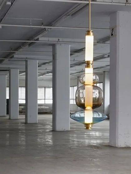 A single, large-scale Luna Kaleido pendant hangs in an industrial space, demonstrating its ability to hold its own as a singular statement piece even in a vast, open environment.