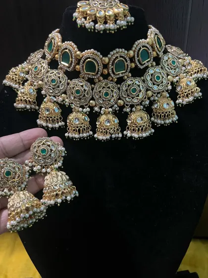 A close-up view of the intricate work on our green choker set. The combination of green stones, white pearls, and gold-tone filigree makes it look incredibly rich.