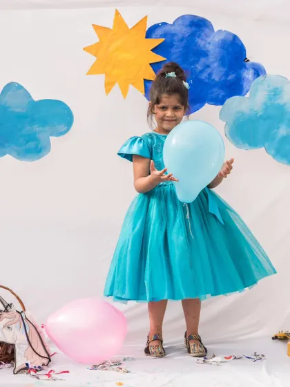 A full-length view of this enchanting turquoise dress. The layered tulle skirt gives it wonderful volume and movement, perfect for a little girl who loves to dance.