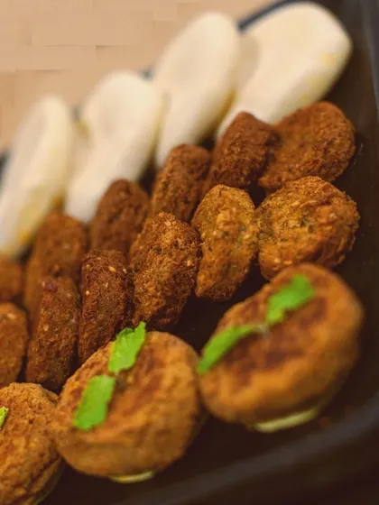 A close-up on the stars of my Lebanese platter: the falafel and pita. This shot highlights the golden-brown, crispy texture of the falafel and the soft, fluffy mini pita breads, perfect for dipping and scooping.