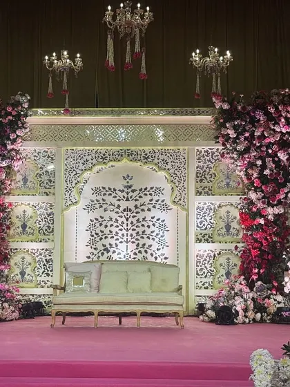 An ethereal stage setting where shades of pink and red florals cascade down pillars against a traditional Indian backdrop. The interplay of lush florals and intricate patterns creates a celestial setting for a celebration.