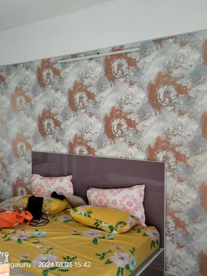 An abstract floral wallpaper in shades of orange and grey, installed in a bedroom.