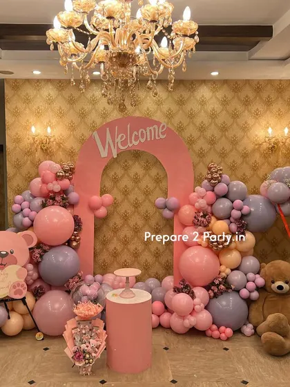 Another perspective of the grand welcome home setup, showing the full scale of the balloon decorations, the central pink arch, and the placement of props in the room.