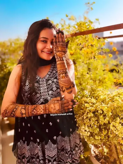 The client smiling and posing, giving a great view of her full-arm mehandi design.