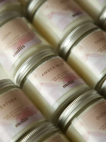 These custom-labeled 100g soy wax candles in scents like Oudh, Amber Musk, and Leather make for adorable baby announcement favors.