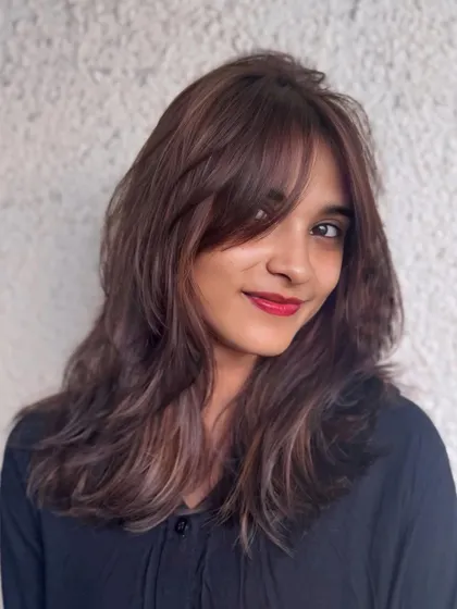 A smiling portrait showcasing the soft layers and subtle brown highlights of this chic, modern hairstyle.