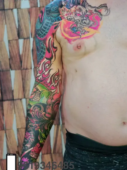 A full sleeve and chest tattoo in a vibrant, Japanese-inspired style. This colorful piece features a dragon and flames, covering a large area of the body with stunning art.
