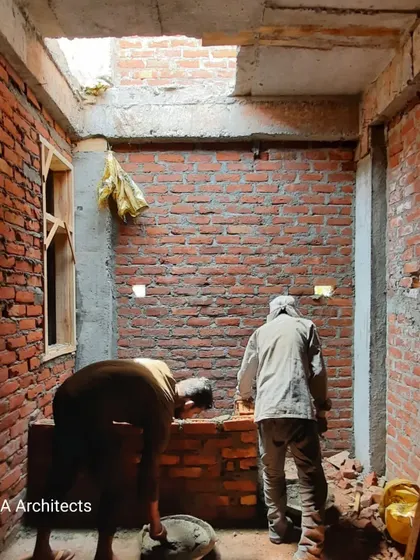 Workers engaged in masonry inside a developing space. This image highlights the skilled labor involved in constructing interior walls and shafts, with natural light entering from a skylight opening.