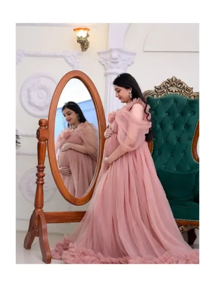A moment of quiet reflection for the mom-to-be. Using props like this vintage-style mirror, I can create artistic and thoughtful portraits. This shot highlights one of our beautiful pink tulle gowns in a royal-themed setting, perfect for a classic and elegant maternity session.