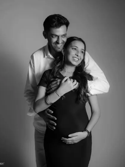 A joyful, candid moment captured in timeless black and white. The couple's laughter and embrace show the happiness and excitement of their pregnancy journey.