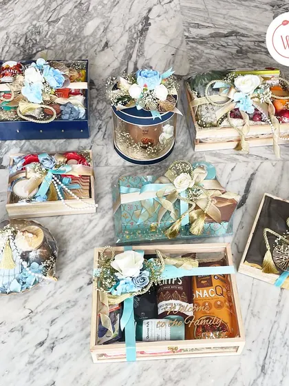 An overhead view of a diverse wedding gifting collection. I can create a cohesive theme across multiple hampers, using elements like color-coordinated florals and consistent packaging materials.