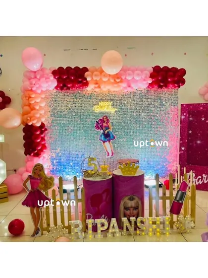 A glamorous Barbie themed birthday setup with a pink sequin wall, a large light-up number '5', and Barbie-themed prop's.