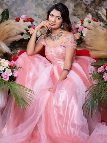 A full view of the seated model in the pink ball gown, showing the impressive volume of the skirt.