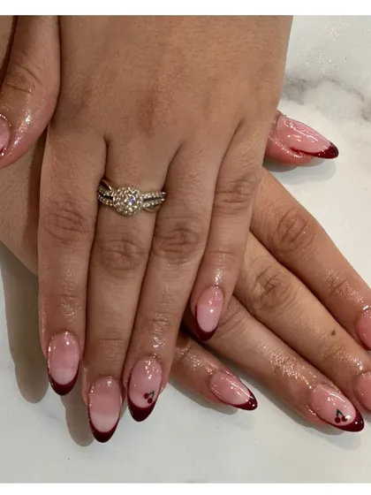 A romantic and moody take on the French manicure. This almond-shaped set features deep red tips with a tiny heart accent on one nail for a subtle, sweet detail.