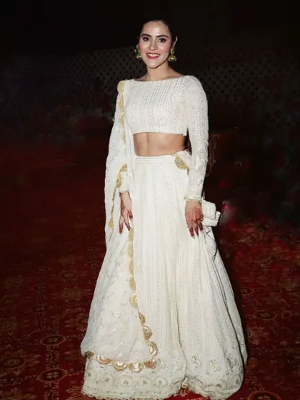A happy client looking absolutely radiant in a custom white Chikankari lehenga. This full-sleeve blouse and detailed skirt with gold borders is a testament to timeless elegance, perfect for any grand celebration.
