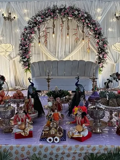 A beautiful lavender-themed platter decoration for an engagement. The entire setup, from the dolls to the fruit baskets, is coordinated with the purple floral decor of the stage.