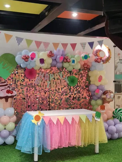 The main table at a Candyland themed party, featuring a shimmering backdrop and a colorful table skirt, ready for the birthday cake and sweets.