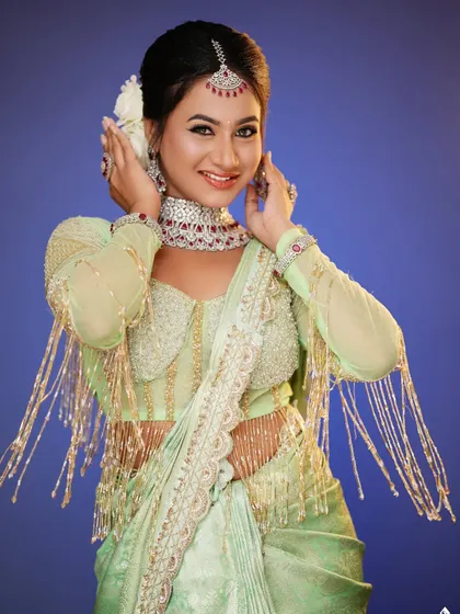 The blue background provides a beautiful contrast to the green outfit and highlights the makeup.