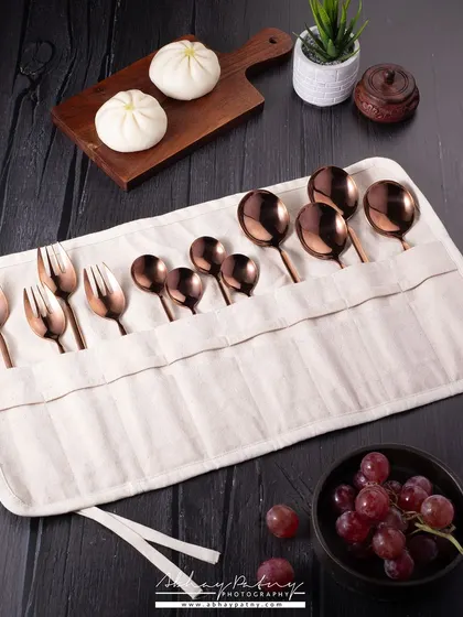 A lifestyle shot of a beautiful copper cutlery set in its travel pouch. I've included food items like bao and grapes to show the product in a realistic use-case scenario.