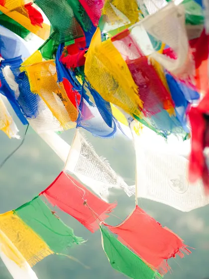 A close-up of the prayer flags, fluttering in the wind. The bright colors against the sky are a symbol of hope and peace.