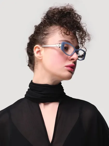 A striking studio portrait for IDEE Eyewear. The focus is entirely on the model's expression and the sharp, architectural design of the glasses, creating a clean and modern fashion statement.