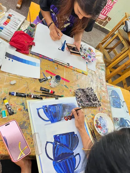 An overhead view of our busy studio table. Students work on their individual still life projects, learning about monochrome painting and how to render reflective surfaces.