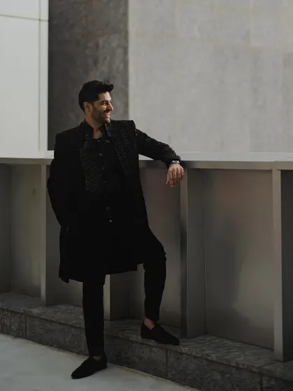 A stylish portrait of the groom leaning against a modern architectural element in Mumbai, smiling casually. This shot highlights our ability to capture fashionable and relaxed individual portraits.