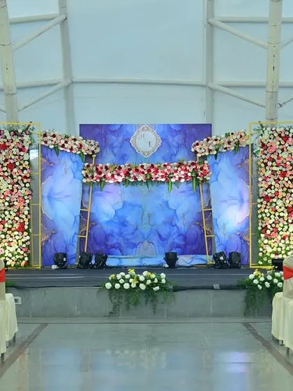 A stunning stage setup for a resort wedding. The floral walls and blue-lit panels create a dramatic and modern look.