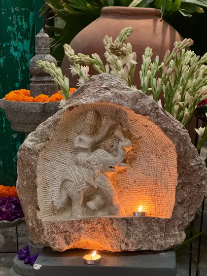 A niche carving of Indra on his elephant Airavata, illuminated by diyas during a Sankranti celebration.