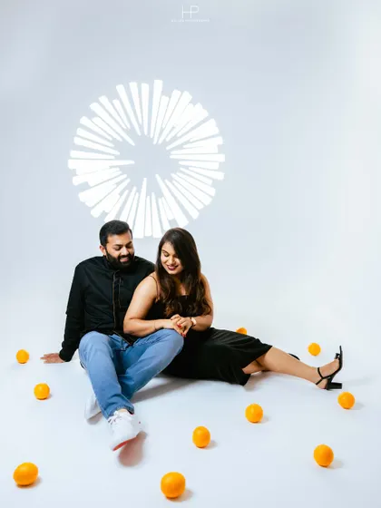 A sweet, romantic moment from a studio session, with the couple seated amidst scattered oranges. The soft interaction shows their gentle connection.