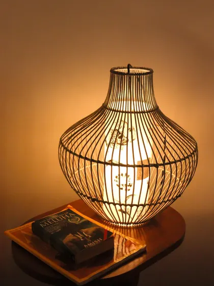 This elegant table lamp features a delicate bamboo cage design. The inner shade casts a soft, patterned light, creating a cozy and sophisticated atmosphere perfect for a reading nook.