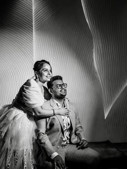 An architectural portrait in black and white. The dramatic lighting and curved lines of the wall create a modern and artistic backdrop for the couple.