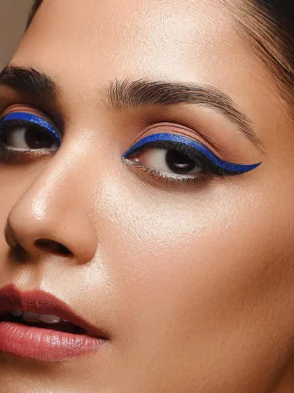 This shot is all about color and precision. The sharp, winged blue eyeliner provides a pop of color against the natural skin, perfect for showcasing a specific makeup product or a bold editorial look.