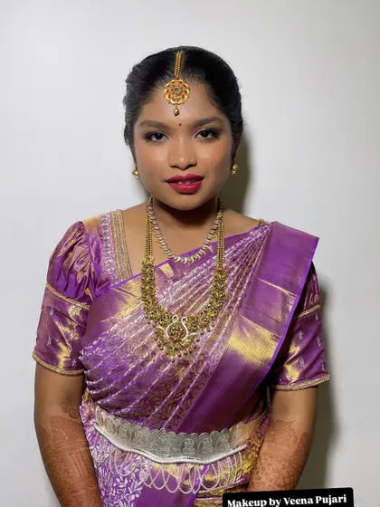 A beautiful client in a rich purple silk saree. The makeup features a bold berry lip and defined eyes, creating a look that is both traditional and striking.