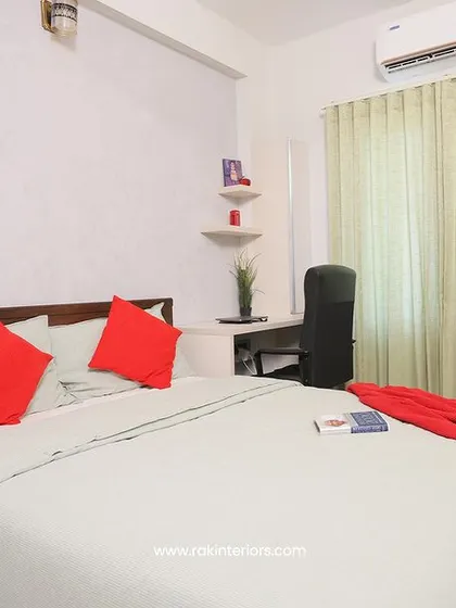 A simple guest bedroom with a white and red color scheme. The room is designed for comfort and functionality, with a small desk area for convenience.