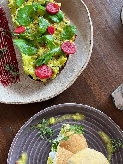 A beautifully plated avocado toast. The artistic presentation and vibrant colors make this a highly appealing shot for a cafe's brunch menu.