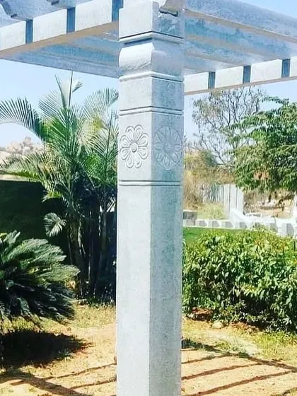 A beautiful stone pergola with carved pillars, set in a lush garden. This is a great way to add a touch of classic elegance to your landscape.