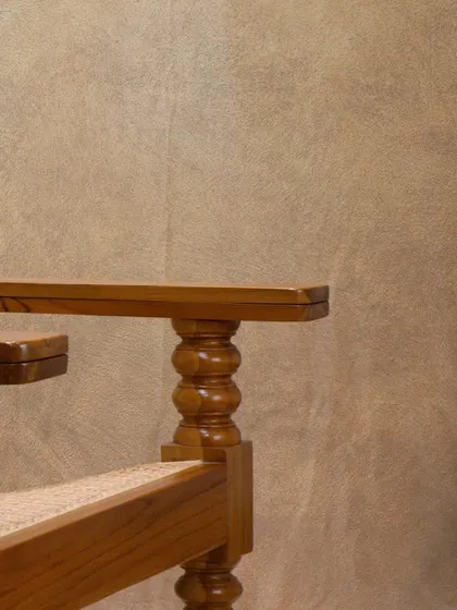 The armrest and turned leg detail of the 'Orca' lounge chair, showcasing the solid construction and decorative carving that defines this piece.
